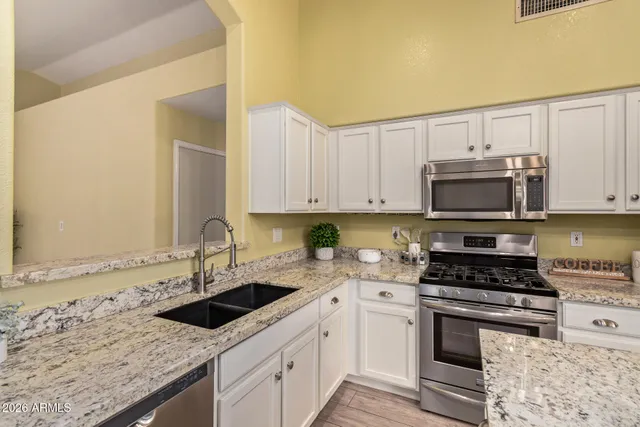 a kitchen with granite countertop a sink a stove and cabinets
