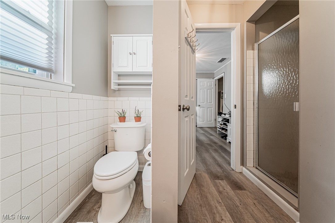 595 Moorfield Road Fairlawn, OH 44313 - Photo 38 of 50 Bathroom with a stall shower, light wood finished floors, tile walls, and wainscoting