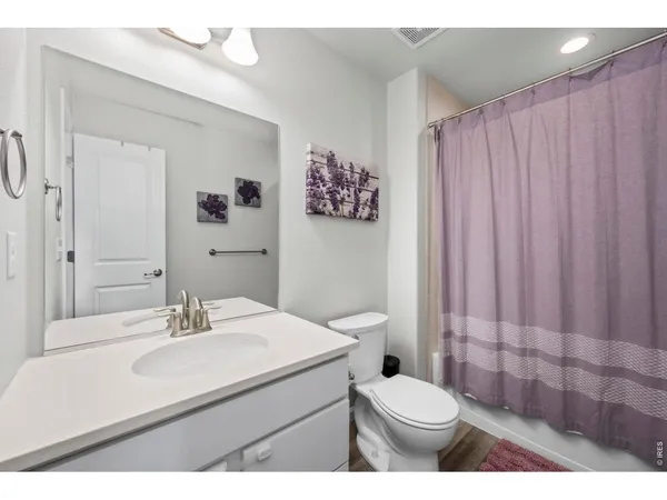 a bathroom with a sink a toilet a mirror and shower curtain