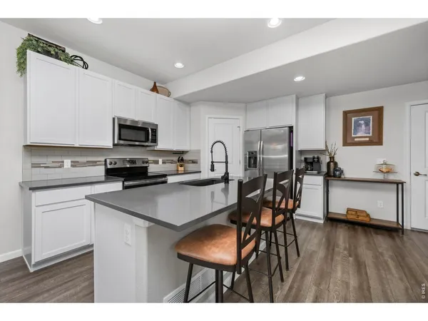 a kitchen with stainless steel appliances a microwave a stove a refrigerator a sink a stove with wooden floor cabinets and dining table