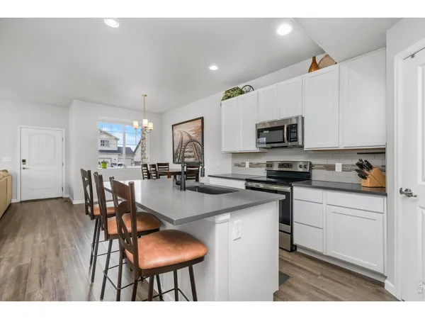 a kitchen with stainless steel appliances a dining table chairs microwave and sink