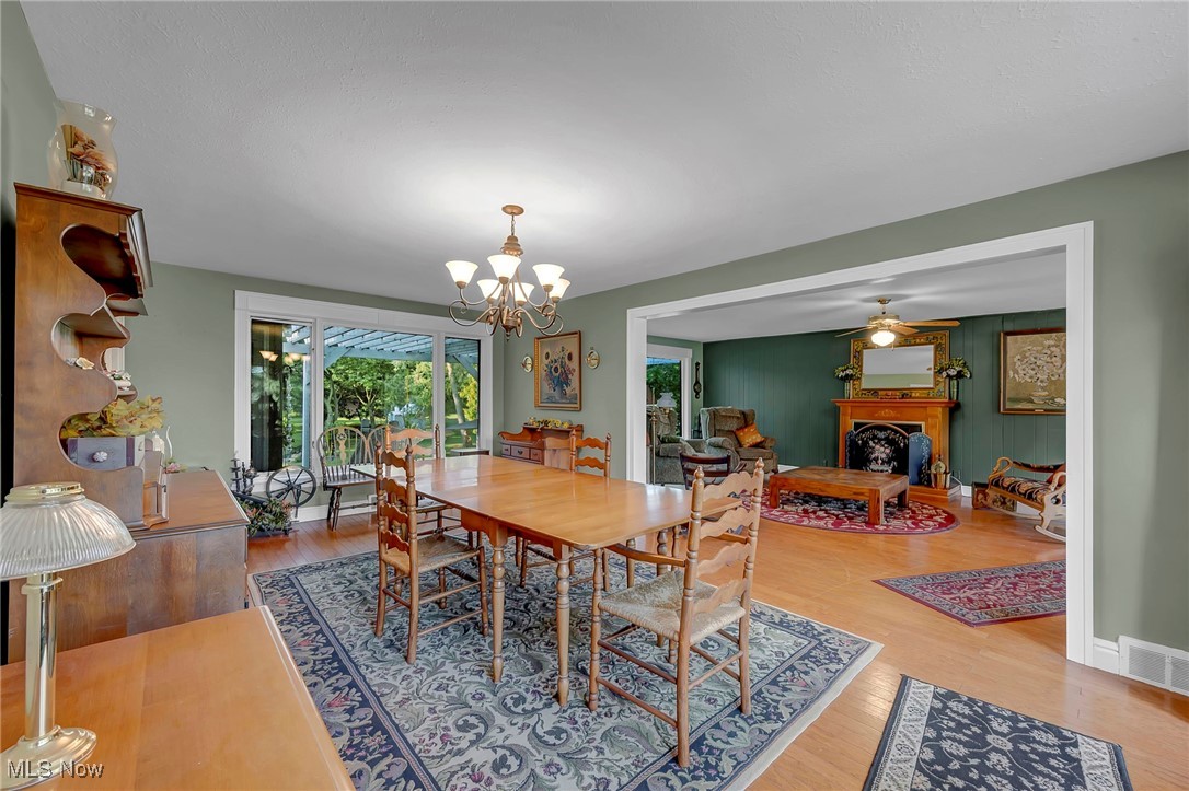 25915 Kennedy Ridge Road North Olmsted, OH 44070 - Photo 15 of 48 Dining area featuring a fireplace, wood finished floors, a chandelier, and a ceiling fan