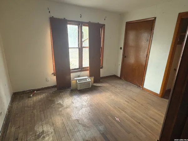 an empty room with wooden floor and windows