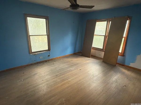an empty room with wooden floor and windows
