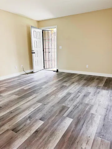 a view of an empty room with wooden floor and a window