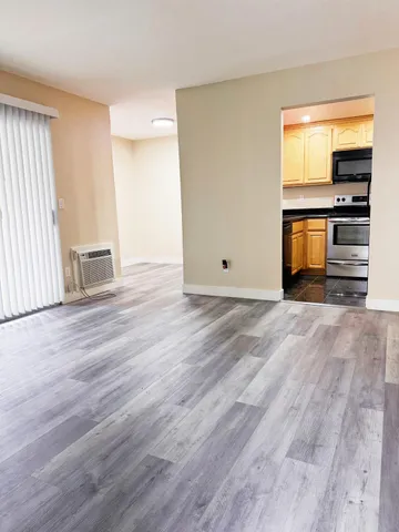 an empty room with wooden floor closet and windows