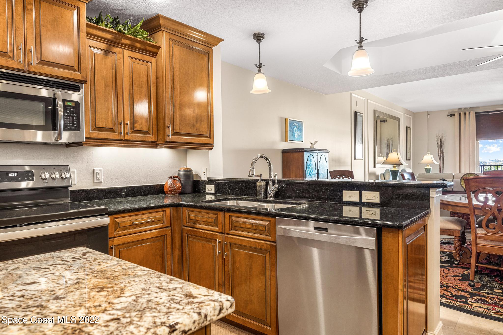 29 Riverside Drive, Unit 302 Cocoa, FL 32922 - Photo 13 of 56 a kitchen with stainless steel appliances granite countertop a sink a stove a refrigerator cabinets and chairs