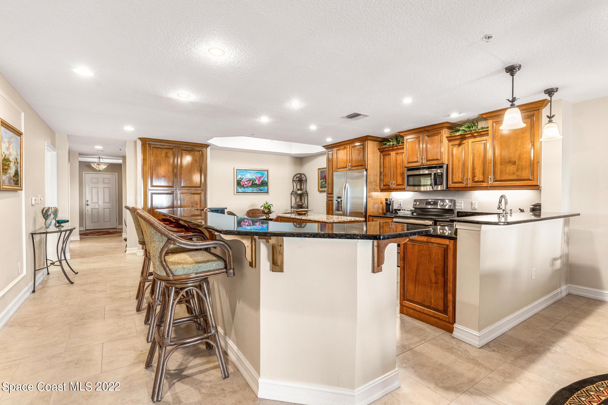 29 Riverside Drive, Unit 302 Cocoa, FL 32922 - Photo 15 of 56 a kitchen with stainless steel appliances kitchen island granite countertop a refrigerator a stove a sink dishwasher with a dining table and chairs with wooden floor