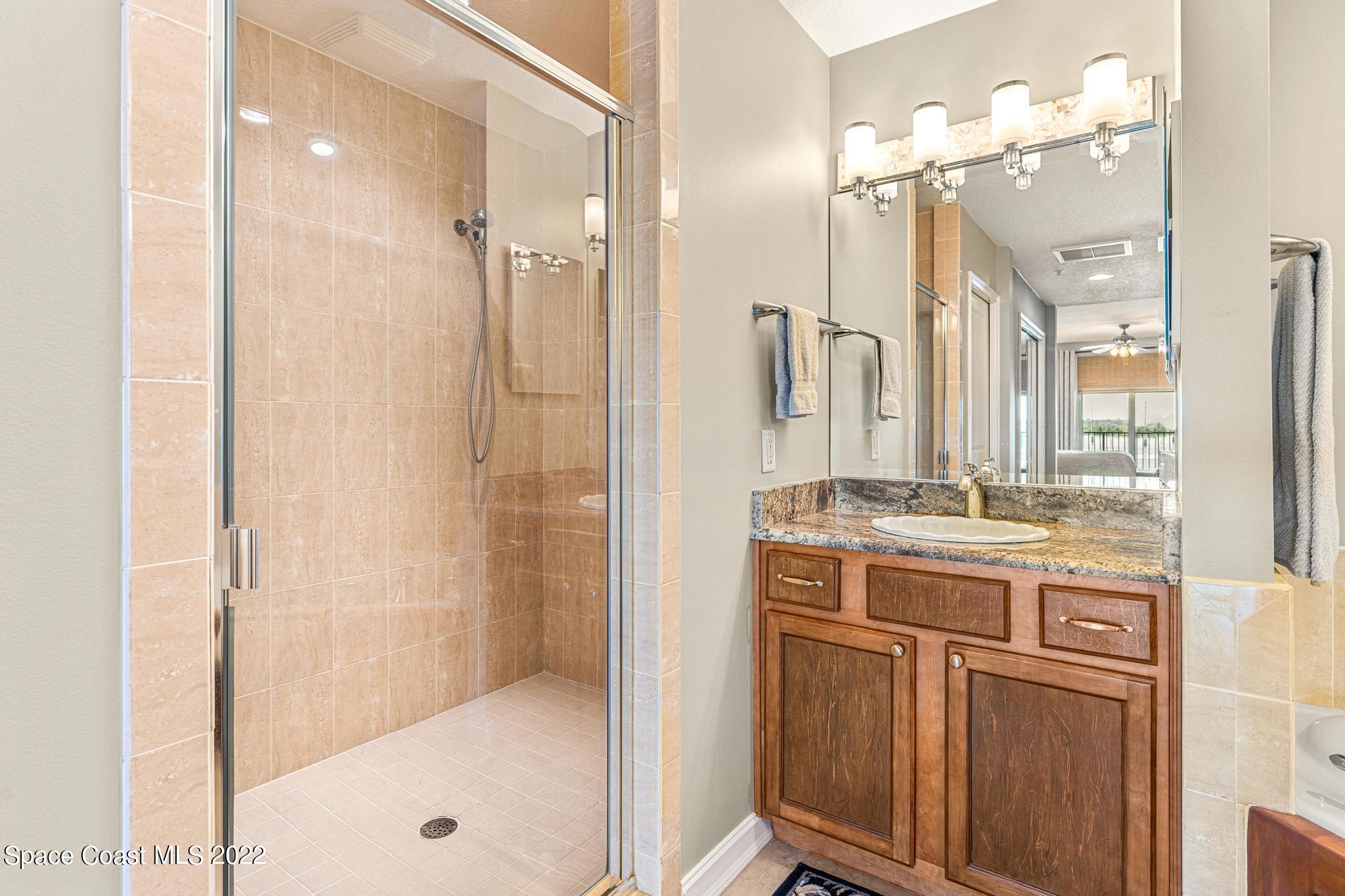 29 Riverside Drive, Unit 302 Cocoa, FL 32922 - Photo 33 of 56 a bathroom with a granite countertop sink a large mirror and shower