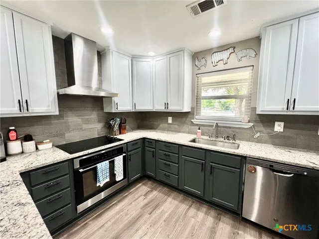 a kitchen with stainless steel appliances granite countertop a sink stove and cabinets