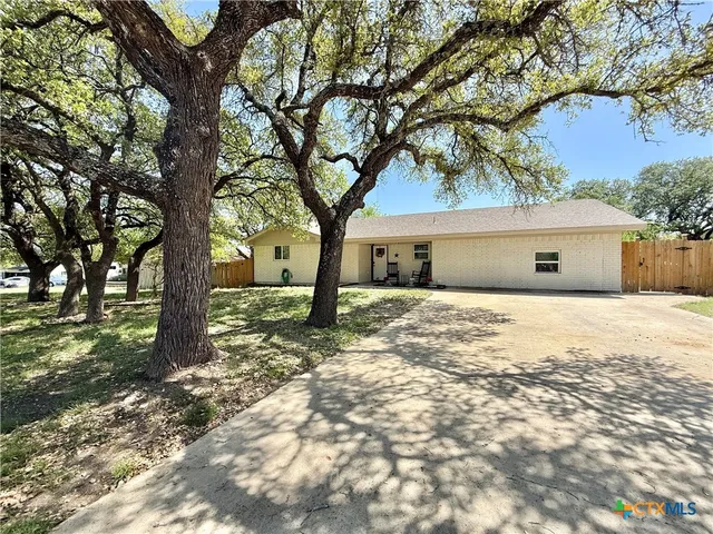 a front view of a house with a yard and large tree