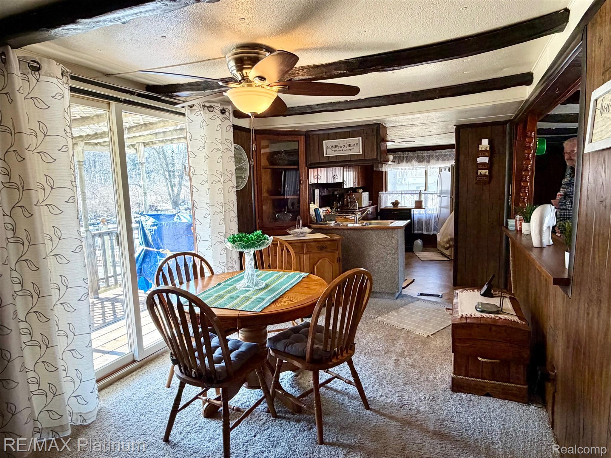 6787 Coon Hill Road Munith, MI 49259 - Photo 5 of 21 Carpeted dining room featuring ceiling fan, beam ceiling, a textured ceiling, and wood walls