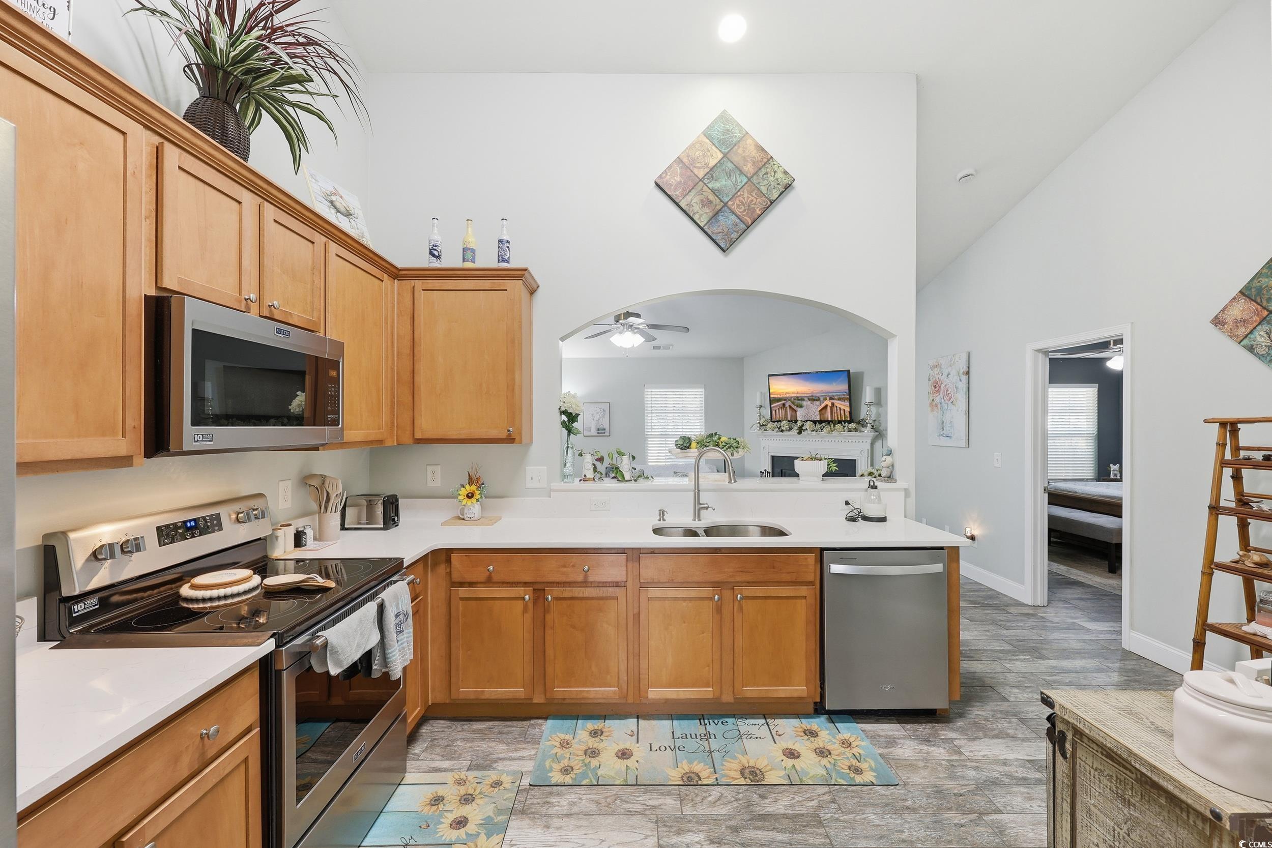 236 Devonbrook Place Longs, SC 29568 - Photo 13 of 40 Kitchen featuring appliances with stainless steel finishes, ceiling fan, high vaulted ceiling, brown cabinets, and light stone countertops