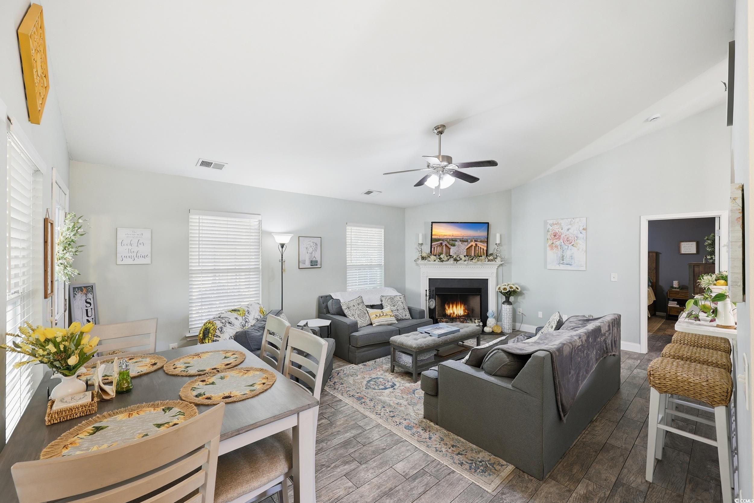 236 Devonbrook Place Longs, SC 29568 - Photo 15 of 40 Living room featuring wood-type flooring, vaulted ceiling, a warm lit fireplace, and a ceiling fan