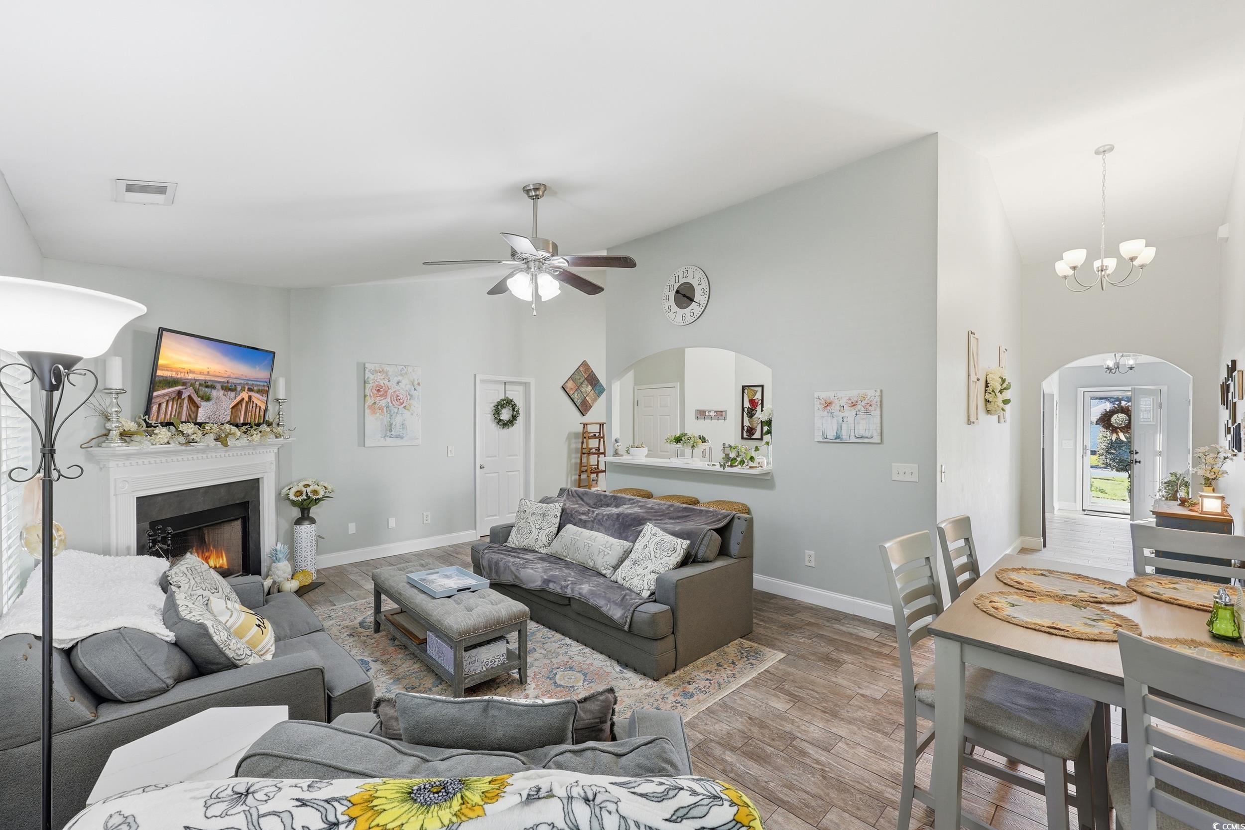 236 Devonbrook Place Longs, SC 29568 - Photo 16 of 40 Living area featuring arched walkways, wood finished floors, high vaulted ceiling, a chandelier, and a lit fireplace