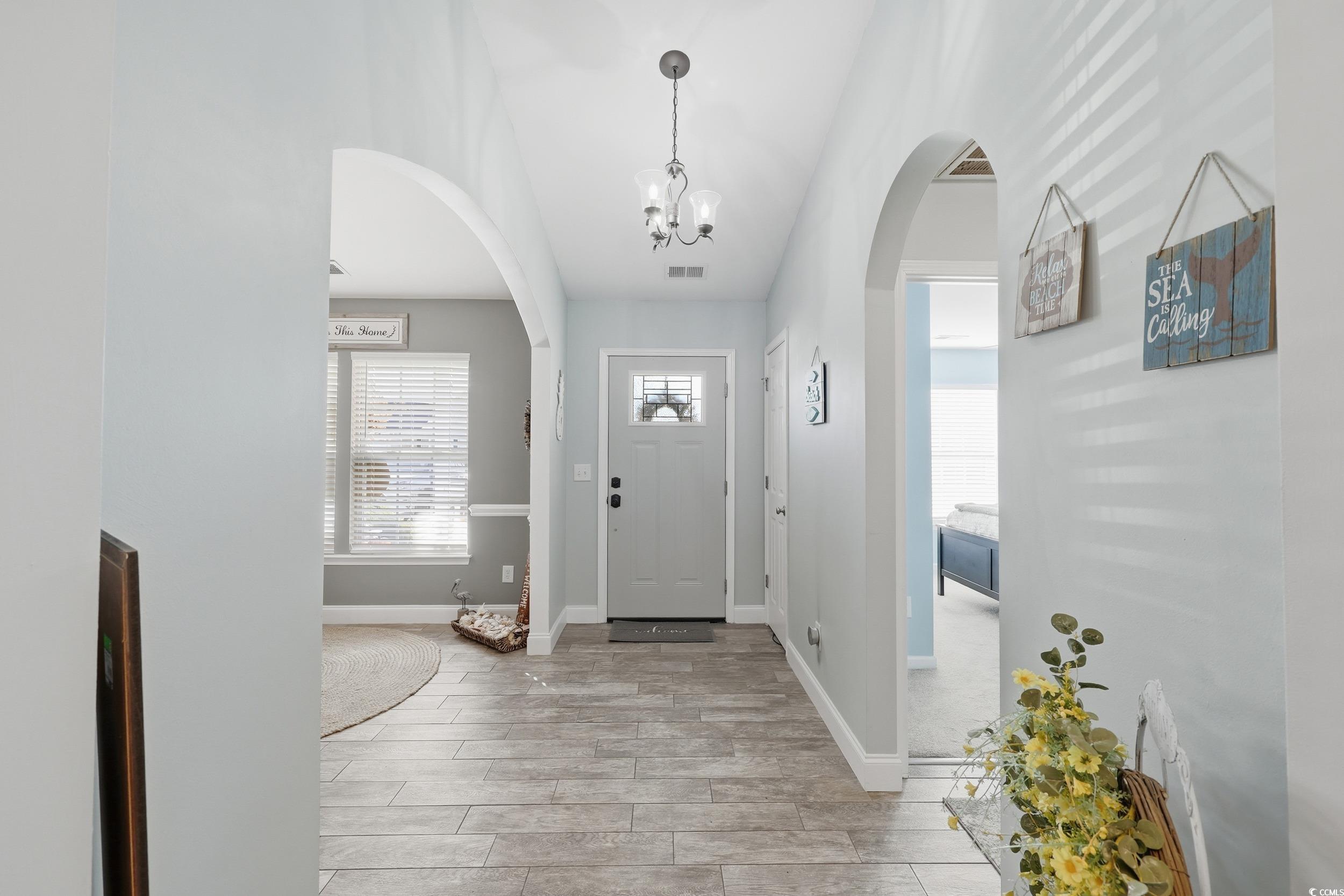236 Devonbrook Place Longs, SC 29568 - Photo 7 of 40 Foyer entrance featuring arched walkways, wood tiled floors, and a chandelier