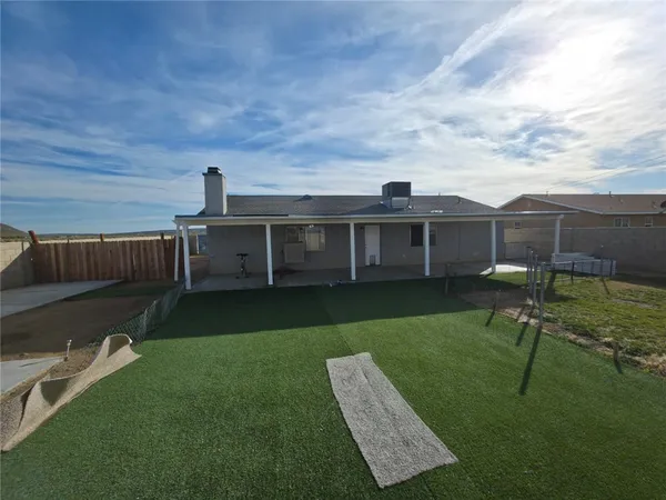 a view of a backyard with couches plants and large tree