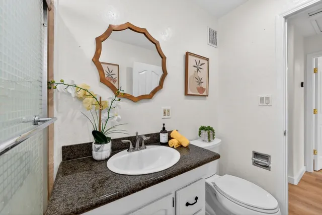 a bathroom with a granite countertop toilet a sink and a mirror