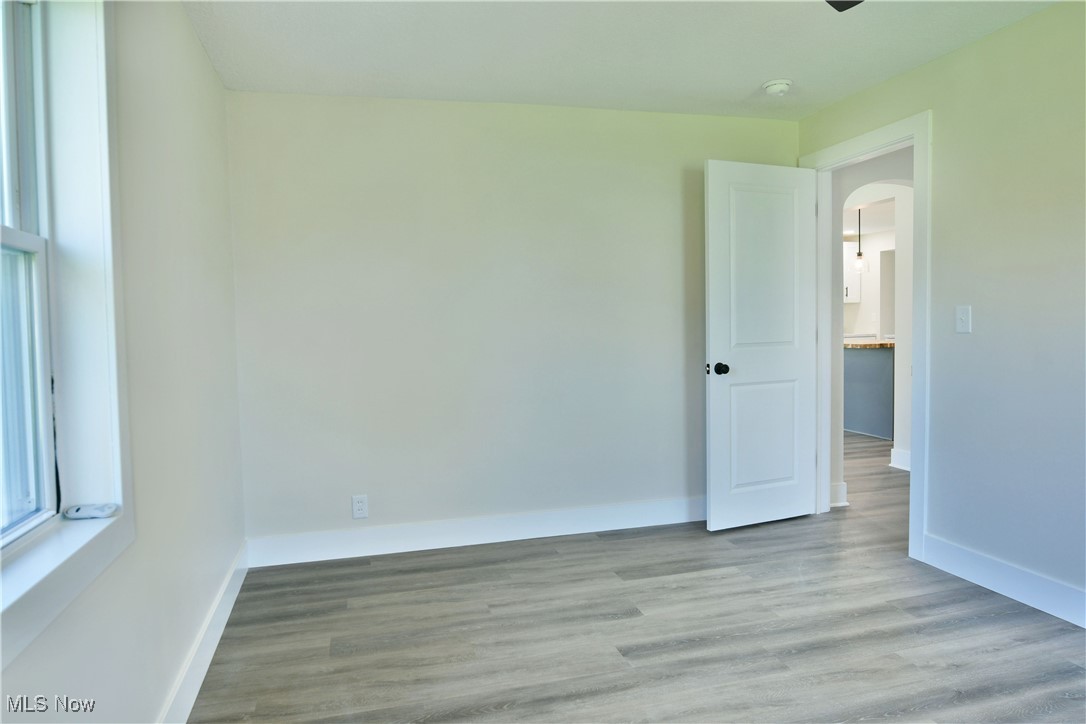 2096 Stillwagon Road Southeast Warren, OH 44484 - Photo 25 of 50 Empty room with arched walkways, baseboards, and wood finished floors