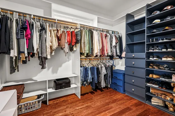 a bedroom with a bed a desk and chair with wooden floor