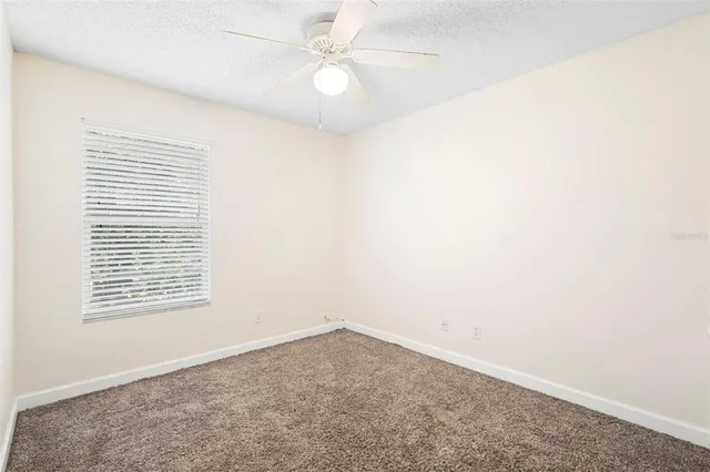 an empty room with a window and a ceiling fan