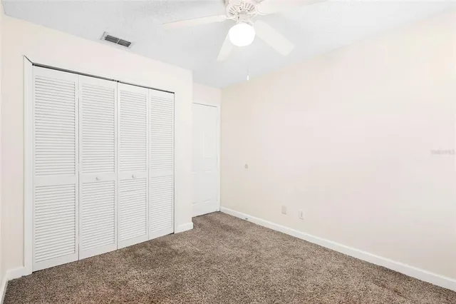 an empty room with a ceiling fan and a window