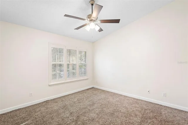 an empty room with a window and a fan