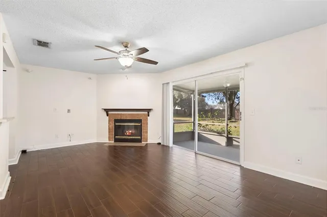 an empty room with wooden floor a fireplace and windows