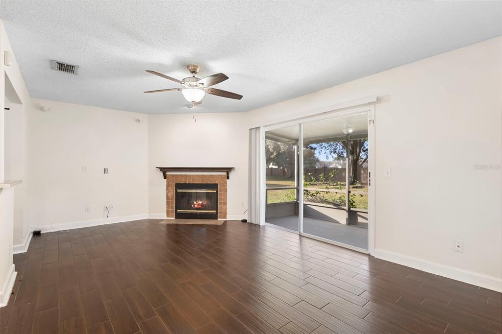 949 Tillery Way, Unit 101 Orlando, FL 32828 - Photo 7 of 38 an empty room with wooden floor a fireplace and windows