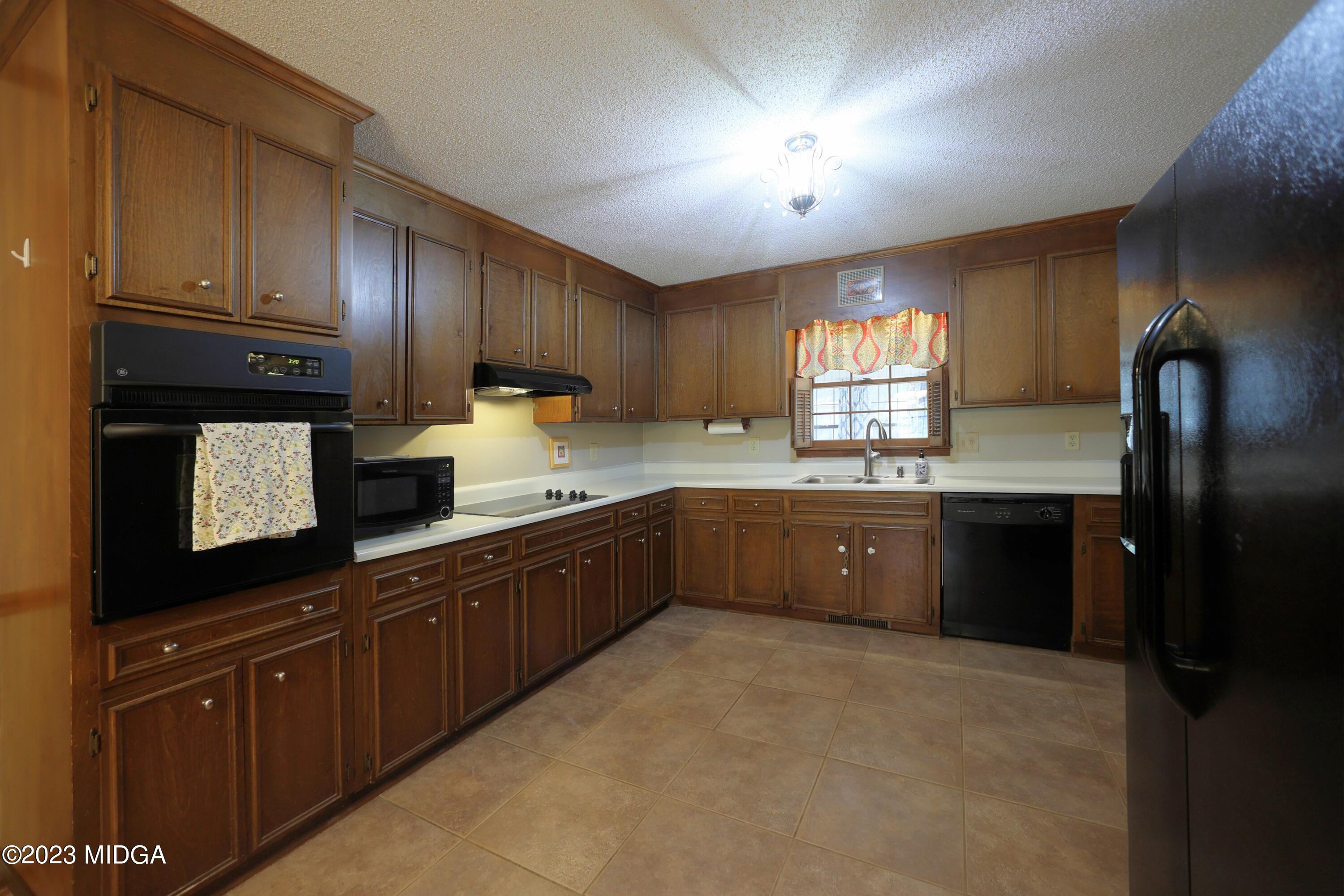 5740 Huddersfield Road Macon, GA 31210 - Photo 17 of 36 a kitchen with granite countertop wooden cabinets a sink a window and stainless steel appliances