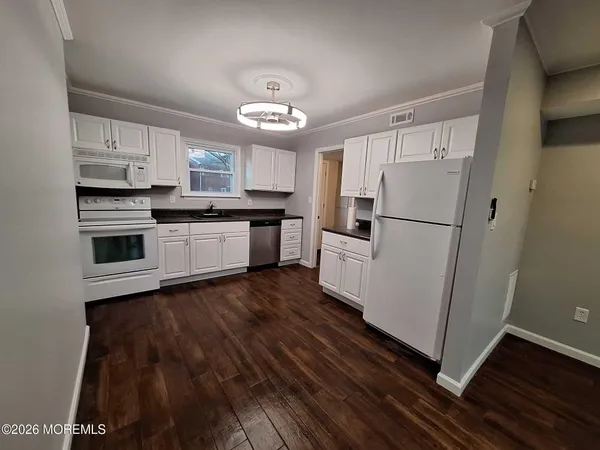 a kitchen with stainless steel appliances a refrigerator a stove a sink and white cabinets