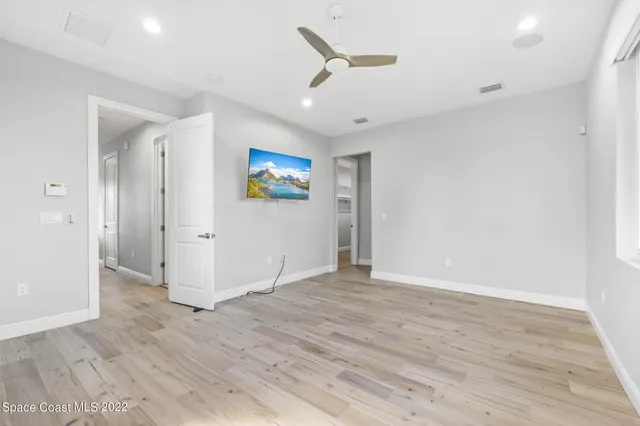 an empty room with wooden floor and ceiling fan
