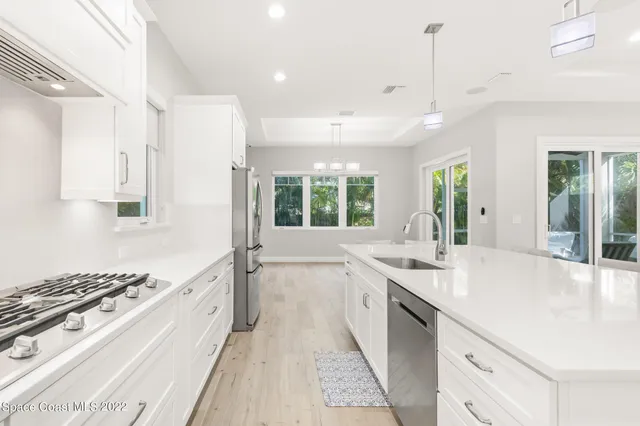 a large white kitchen with a stove and a large window