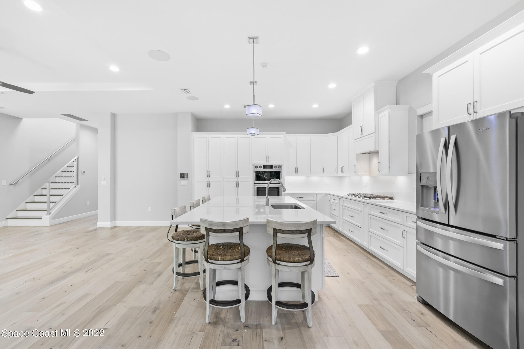 151 24th Street Cocoa Beach, FL 32931 - Photo 5 of 36 a kitchen with stainless steel appliances a refrigerator a stove a dining table and chairs with wooden floor