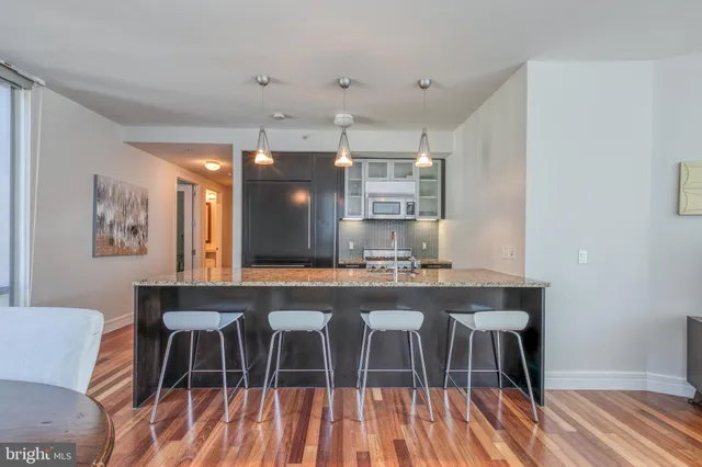 a kitchen with stainless steel appliances a dining table chairs and wooden floor