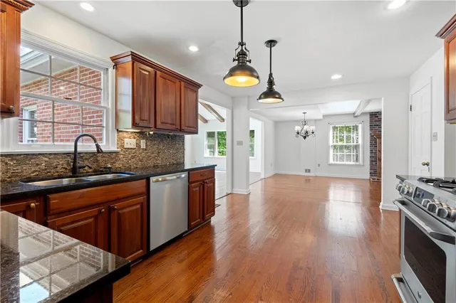 a kitchen with stainless steel appliances granite countertop wooden floors stove and sink