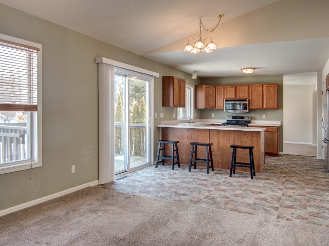 306 Rochester Road Northeast Poplar Grove, IL 61065 - Photo 16 of 25 a kitchen with kitchen island granite countertop a stove a sink a dining table and chairs cabinets