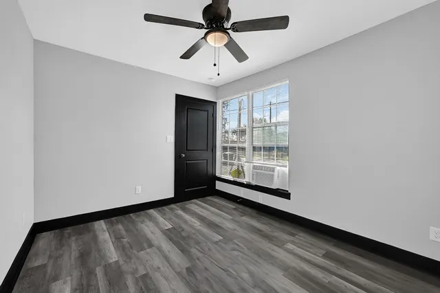 a view of room with window a ceiling fan and wooden floor