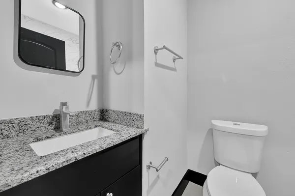 a bathroom with a granite countertop toilet sink and mirror