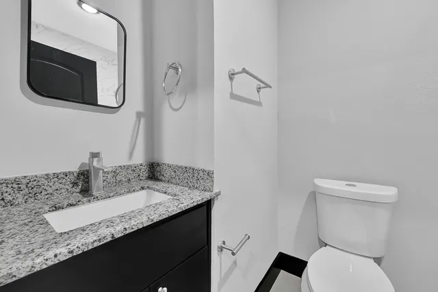 a bathroom with a granite countertop toilet sink and mirror