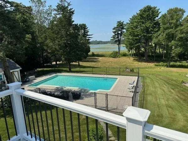 a view of a mini pool with lawn chairs and a big yard