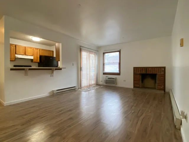an empty room with wooden floor a fireplace and windows