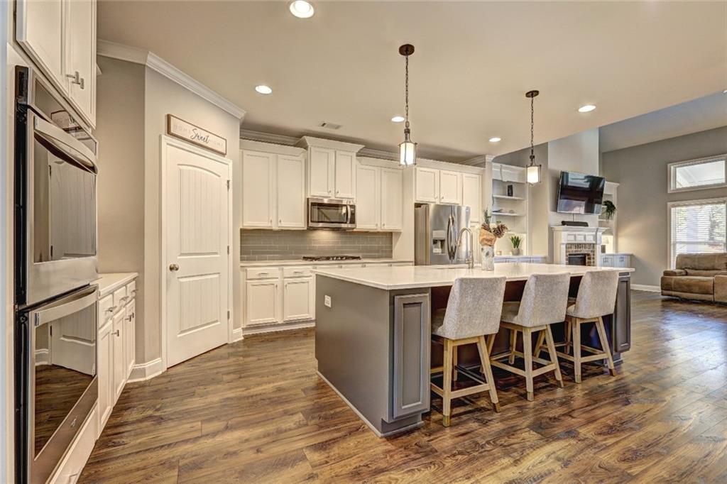 4371 Thacker Lane Suwanee, GA 30024 - Photo 6 of 52 a kitchen with stainless steel appliances kitchen island granite countertop a table chairs and a refrigerator