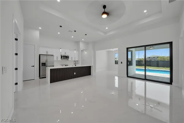 a large white kitchen with a large window and stainless steel appliances