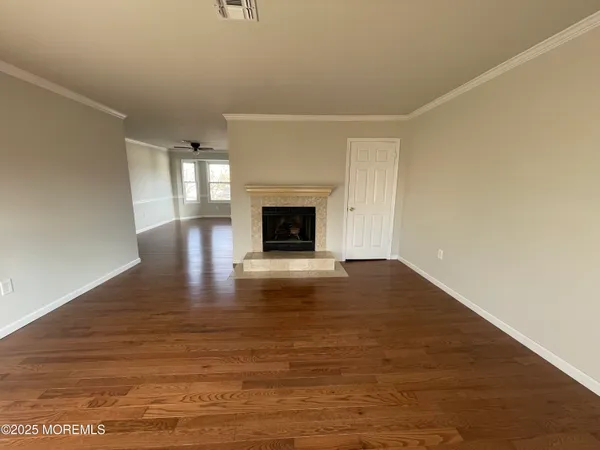 a view of empty room with wooden floor and fireplace