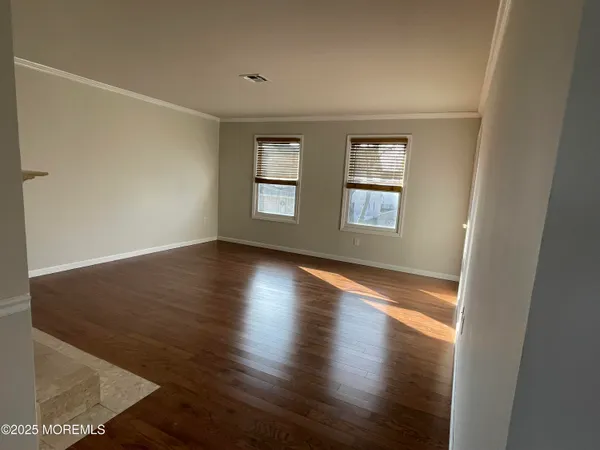 a view of an empty room with wooden floor and window