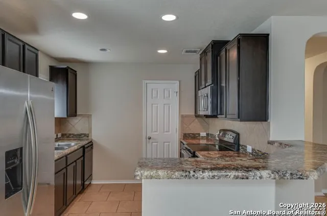 a kitchen with stainless steel appliances granite countertop a refrigerator a stove and a sink