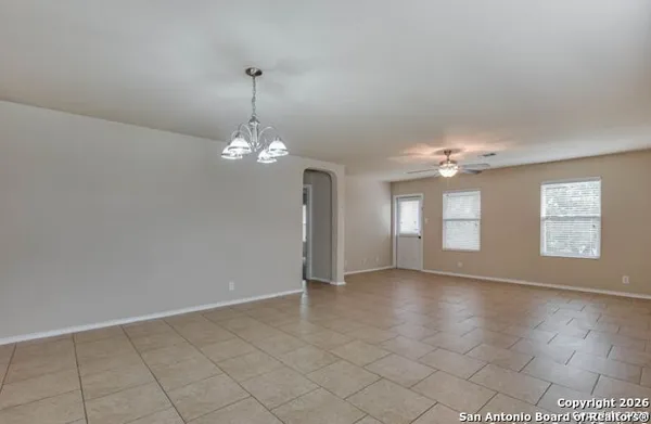an empty room with chandelier fan and windows