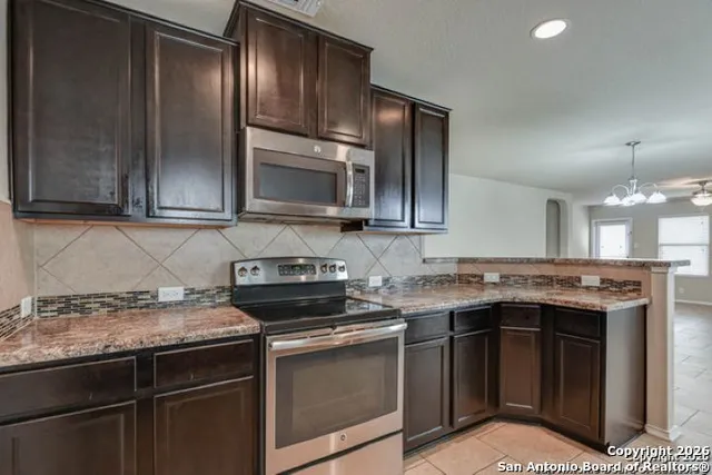 a kitchen with stainless steel appliances granite countertop a stove a sink and a microwave
