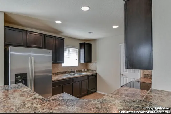 a kitchen with stainless steel appliances kitchen island granite countertop a refrigerator a stove and a sink